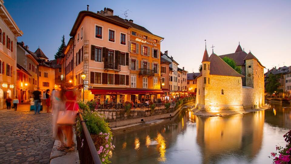 A historic town with a canal, a castle, and traditional buildings with illuminated signs.