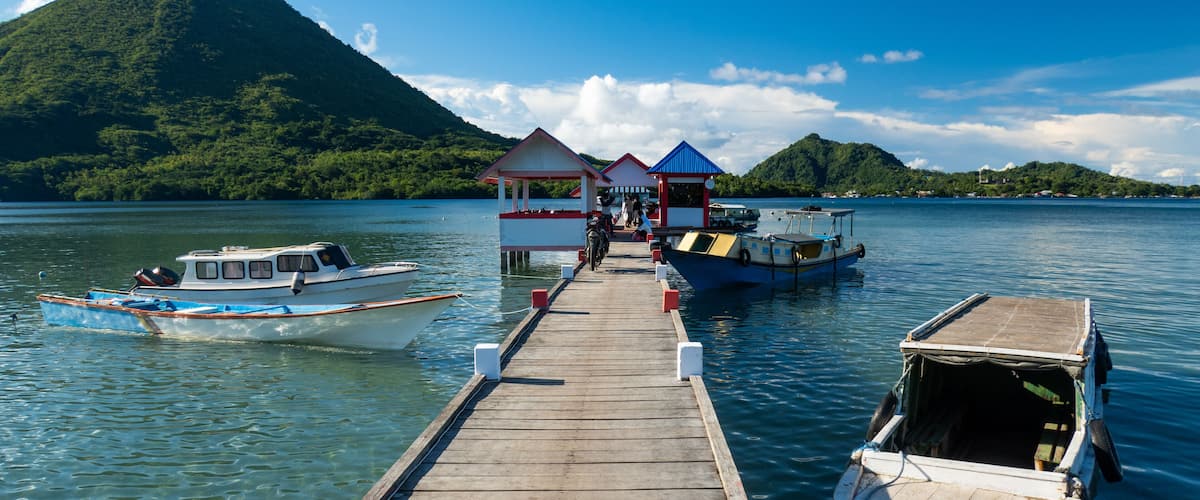 A wooden pier leading to a small island with a mountain in the background.