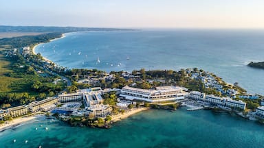 A coastal resort with beachfront villas, a marina, and clear turquoise waters.