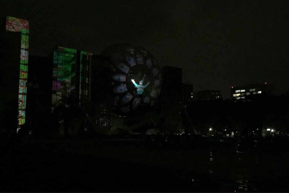 Un paisaje urbano nocturno con edificios iluminados y una estructura esférica grande.