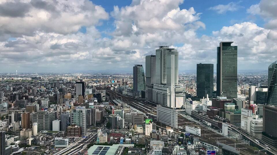 Eine Stadtlandschaft mit modernen Wolkenkratzern, dichter Bebauung und einem Eisenbahnsystem.
