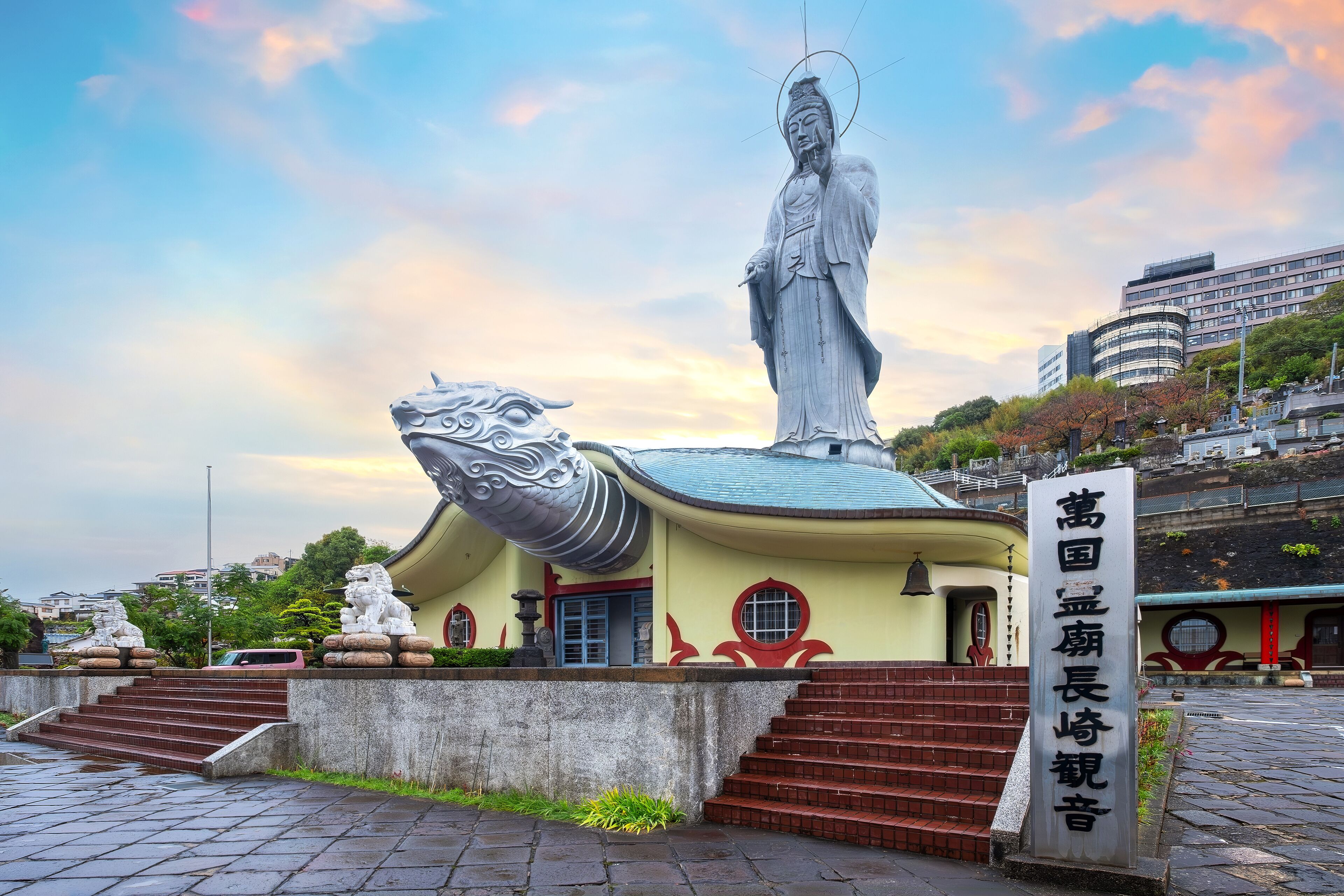 A statue of a figure with a halo, a dragon sculpture, and a building with stairs.