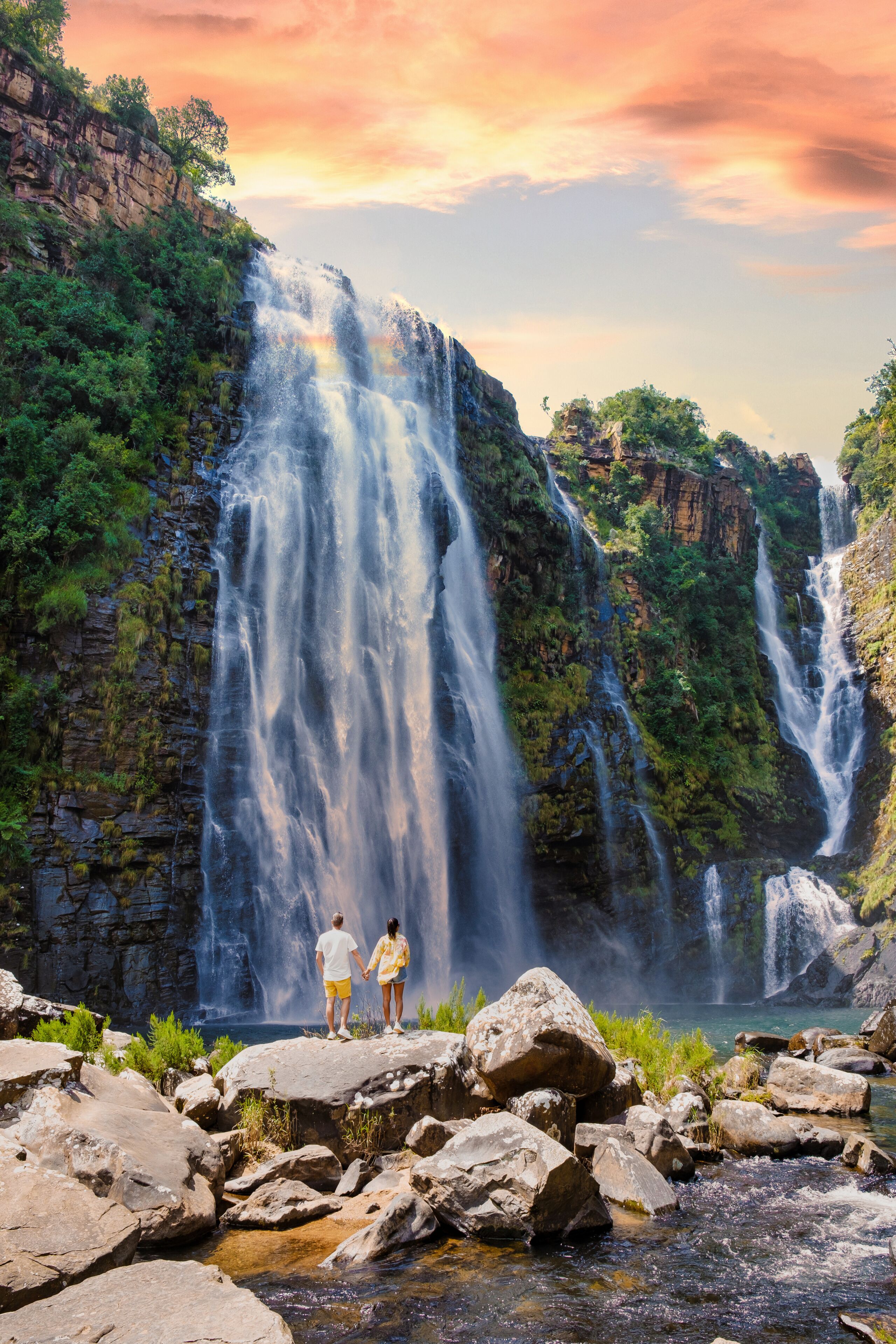 A waterfall cascading down a rocky cliff surrounded by lush greenery.