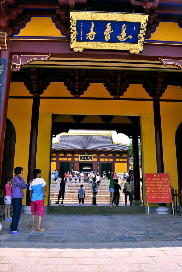 Una puerta tradicional con inscripciones doradas, que da acceso a un complejo de templos.