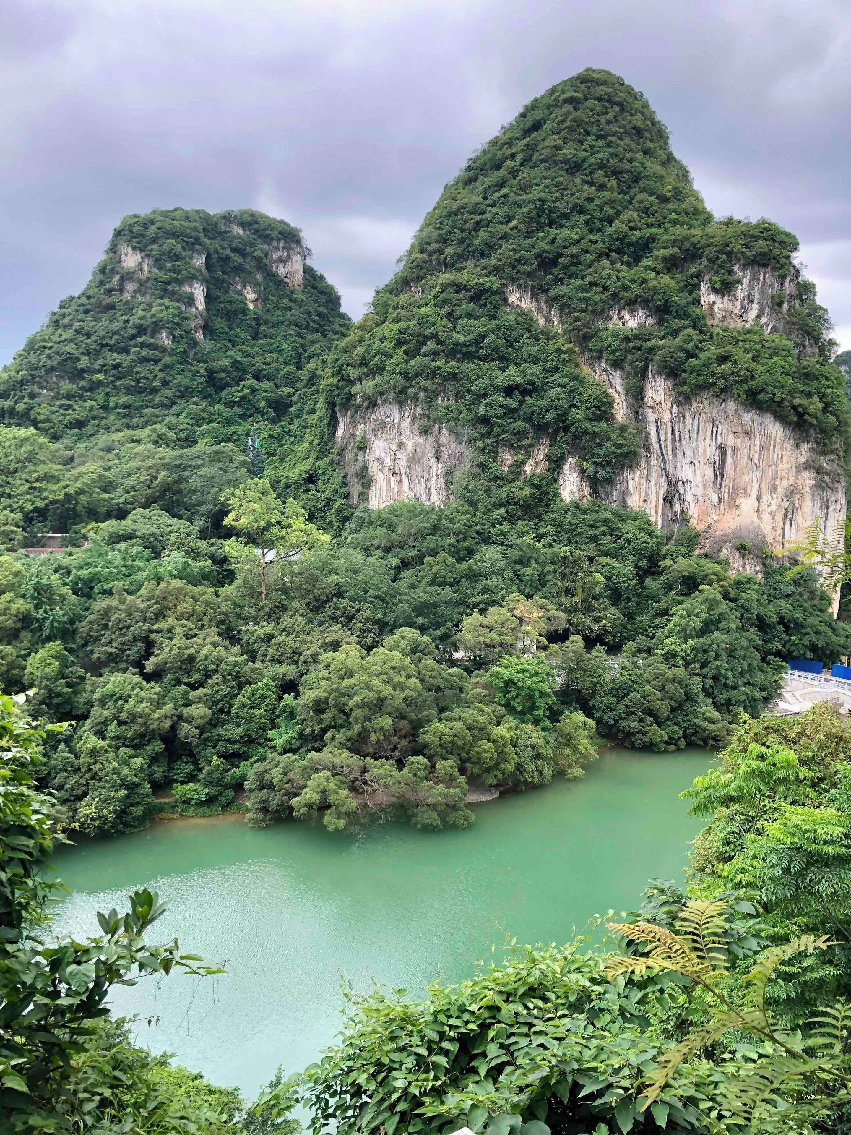 A mountainous landscape with dense green forests and a calm green lake.
