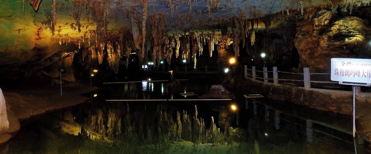 Una cueva con estalactitas y estalagmitas, un pequeño estanque de agua y un letrero en chino.