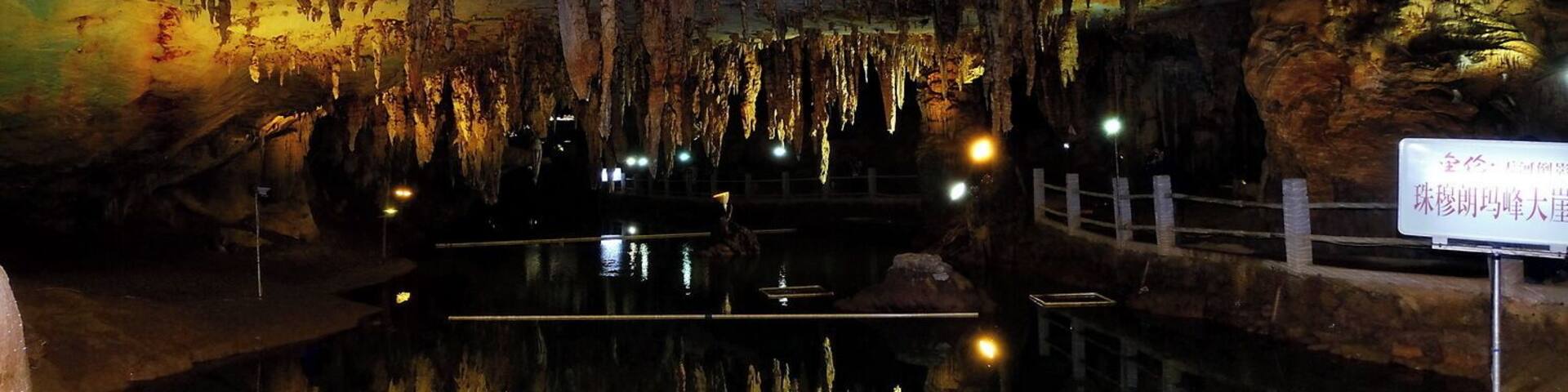 A cave with stalactites and stalagmites, a small pool of water, and a sign in Chinese.