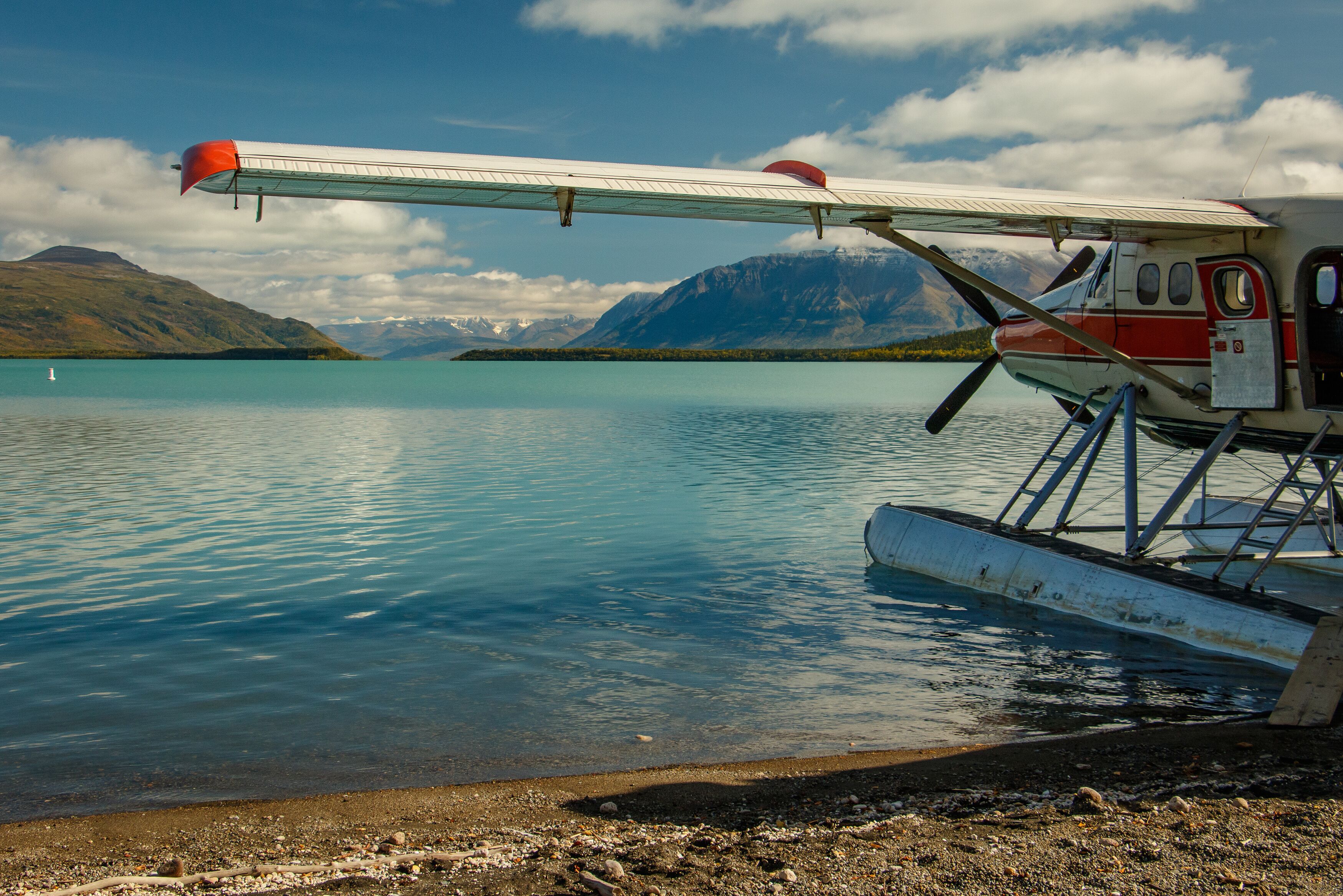 A seaplane parked on a calm lake with mountains in the background.