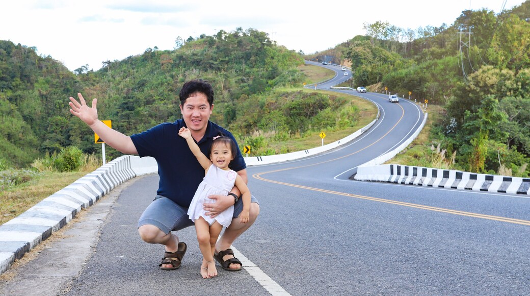 Father and his daughter on roadside with beautiful wavy road in background