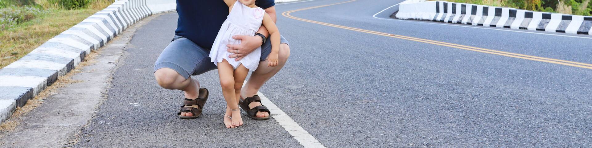 Father and his daughter on roadside with beautiful wavy road in background