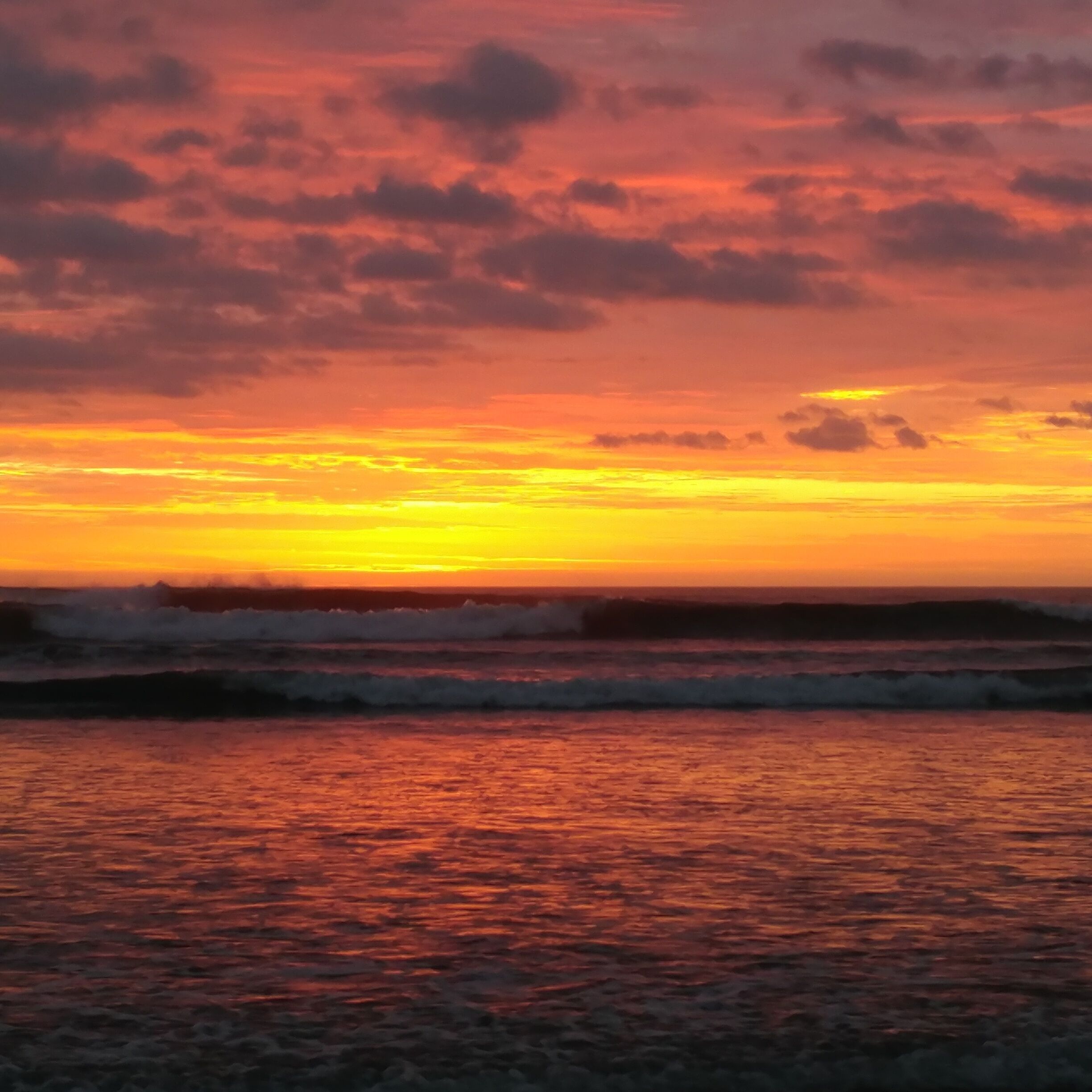 A sunset over the ocean with waves.