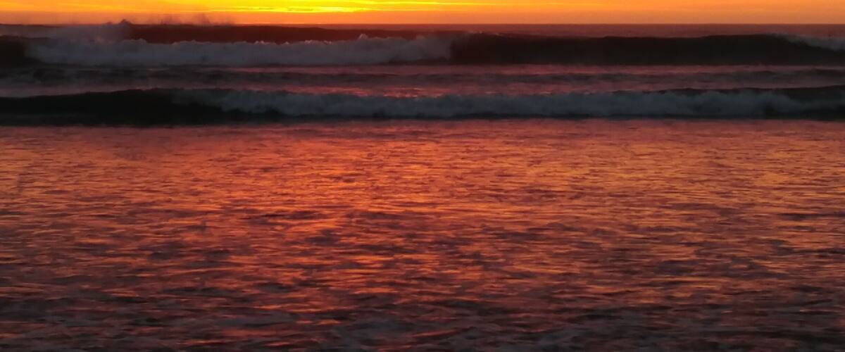 A sunset over the ocean with waves.