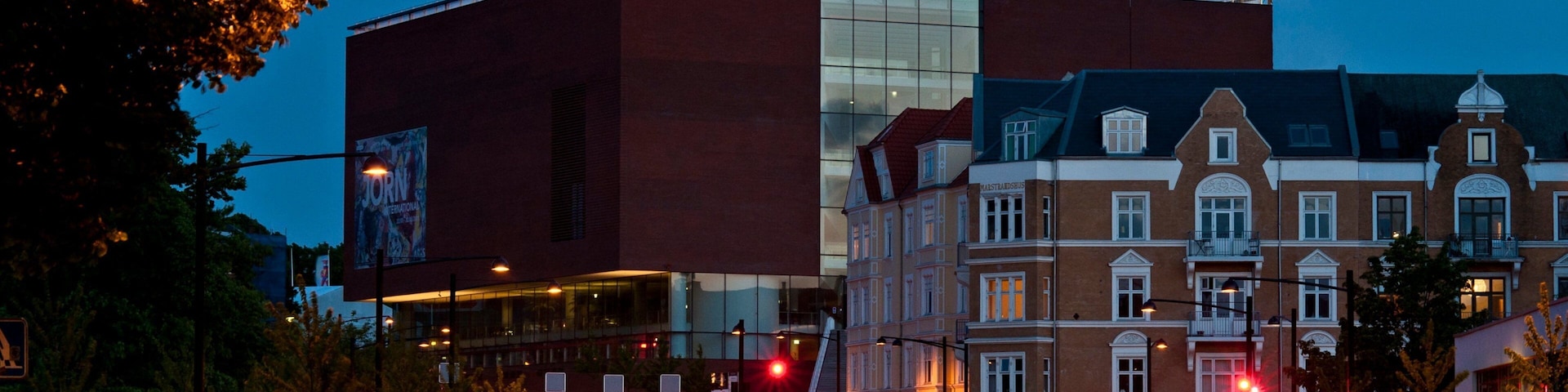 A modern building with a curved glass facade and a colorful circular structure on top.