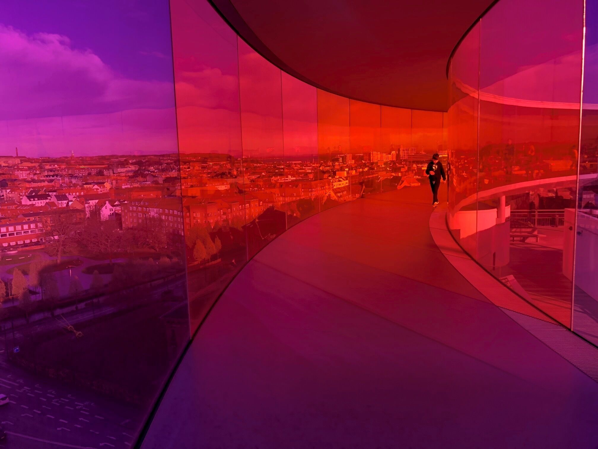 Una persona caminando sobre un puente de cristal, con un paisaje urbano de fondo.