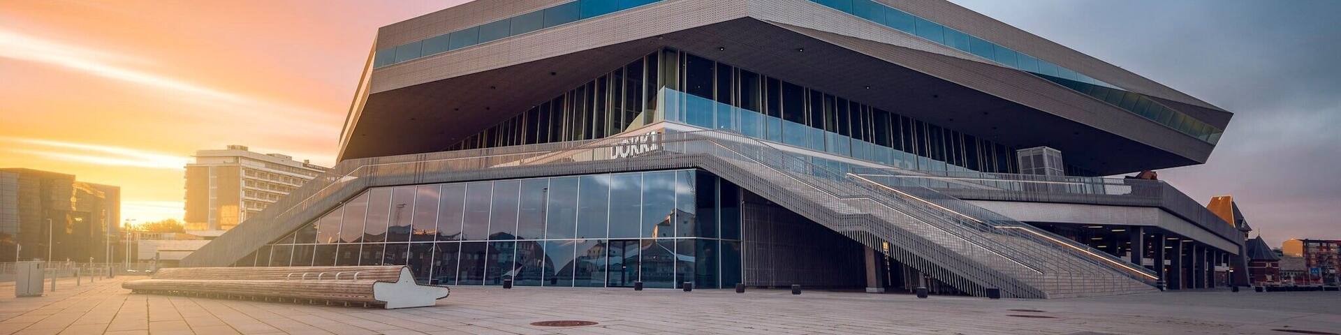 A modern architectural building with a unique design, featuring a prominent staircase leading to the entrance.