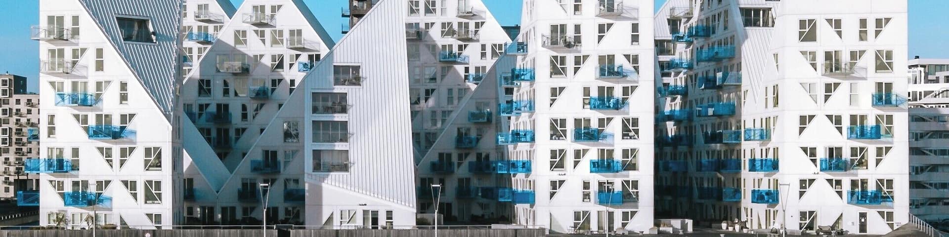 A waterfront with modern buildings featuring geometric designs and balconies.