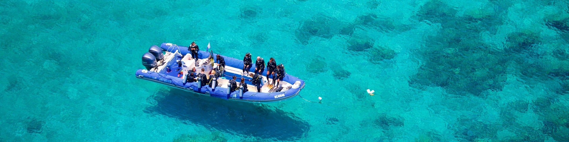 Numea que incluye embarcaciones y vistas de una costa y también un grupo pequeño de personas