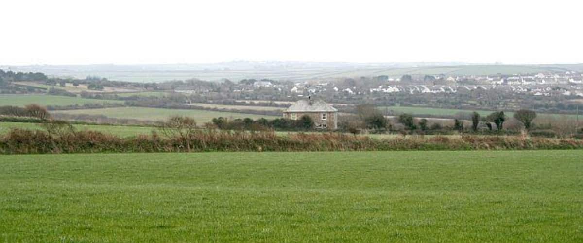 A green field with a small building in the distance.