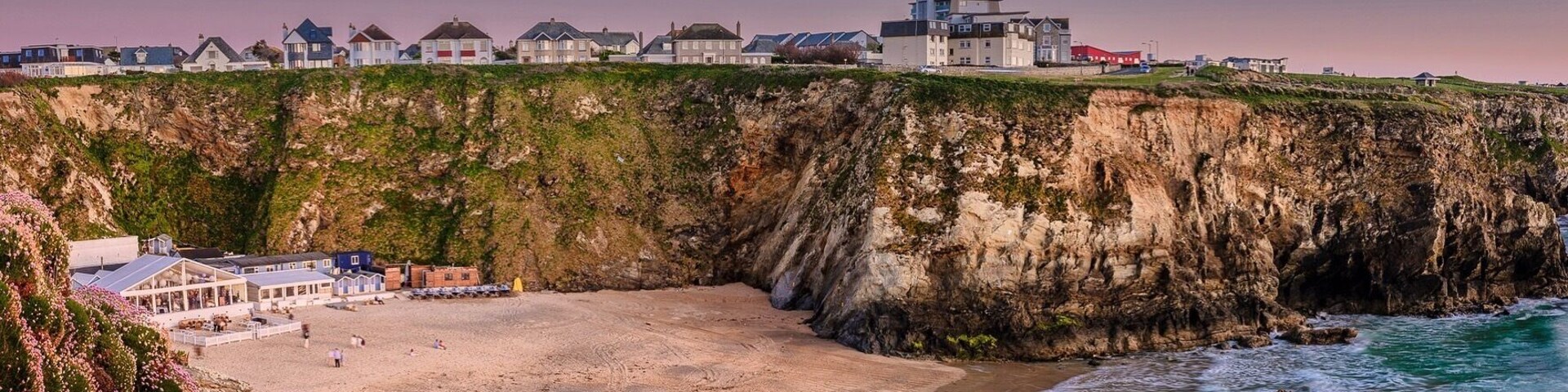 Un pueblo costero con playa, acantilados y casas.