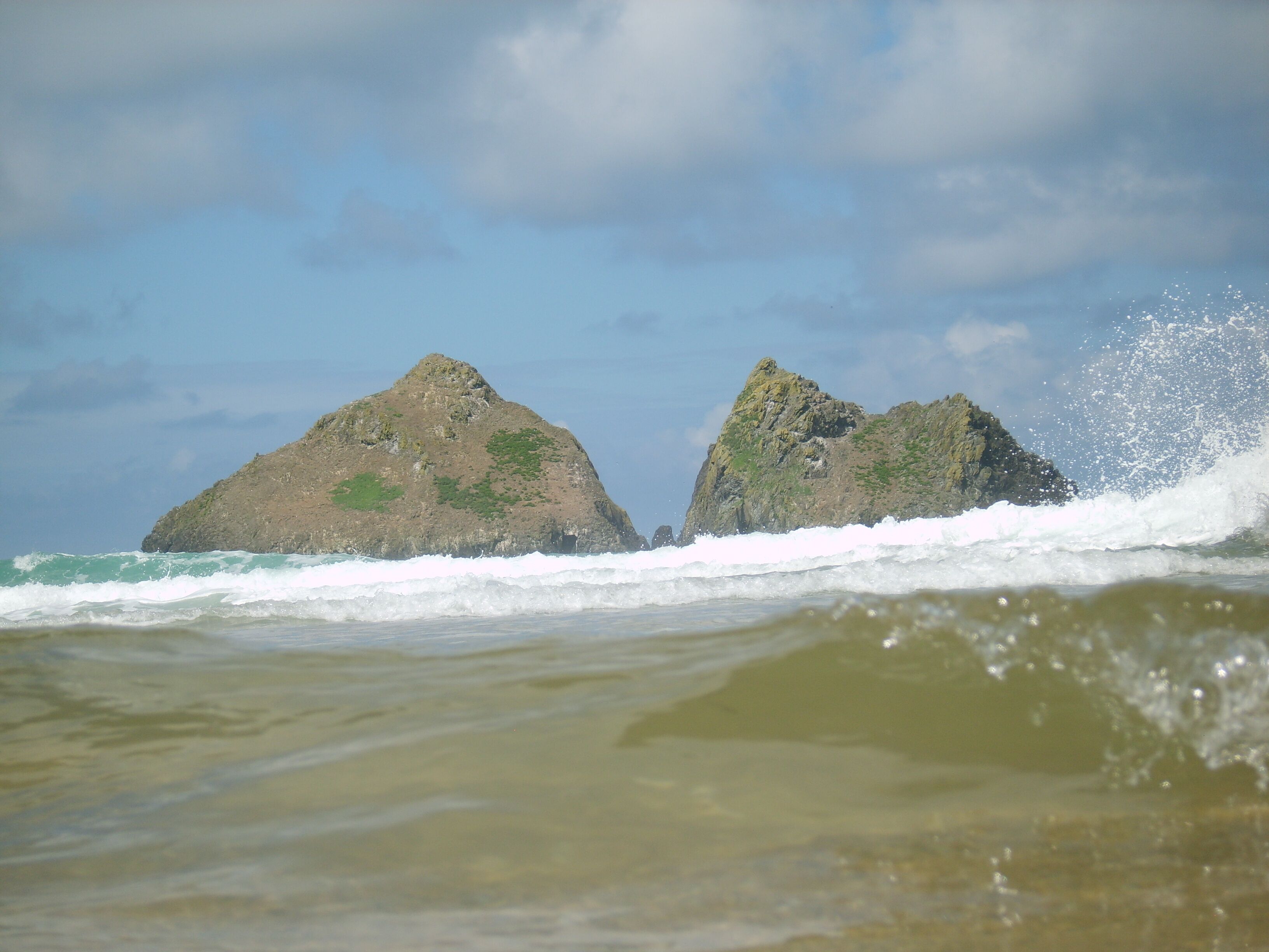 Two rocky outcrops with waves crashing against them.