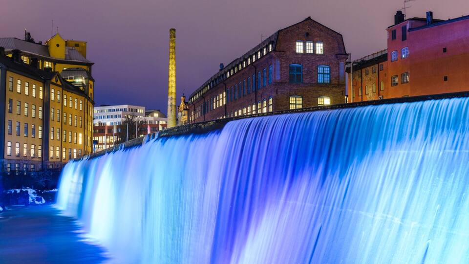 Una cascada grande con edificios al fondo.