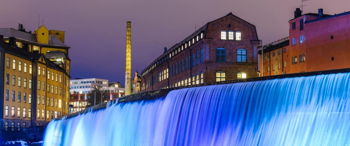 A large waterfall with buildings in the background.