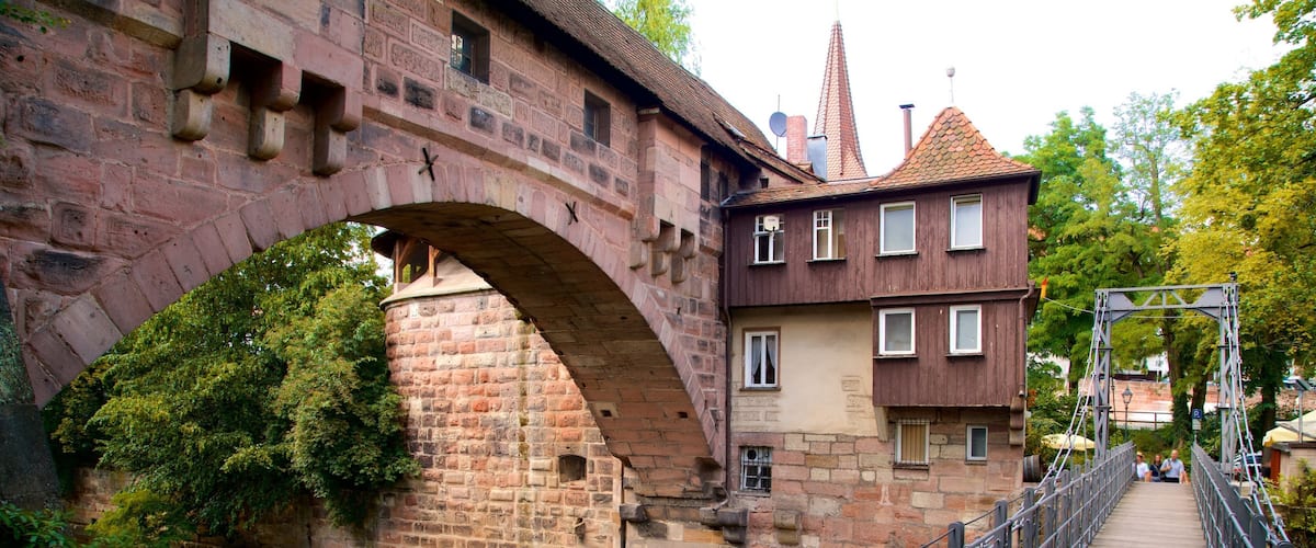 A stone bridge over a river, with a wooden walkway and a historic building in the background.