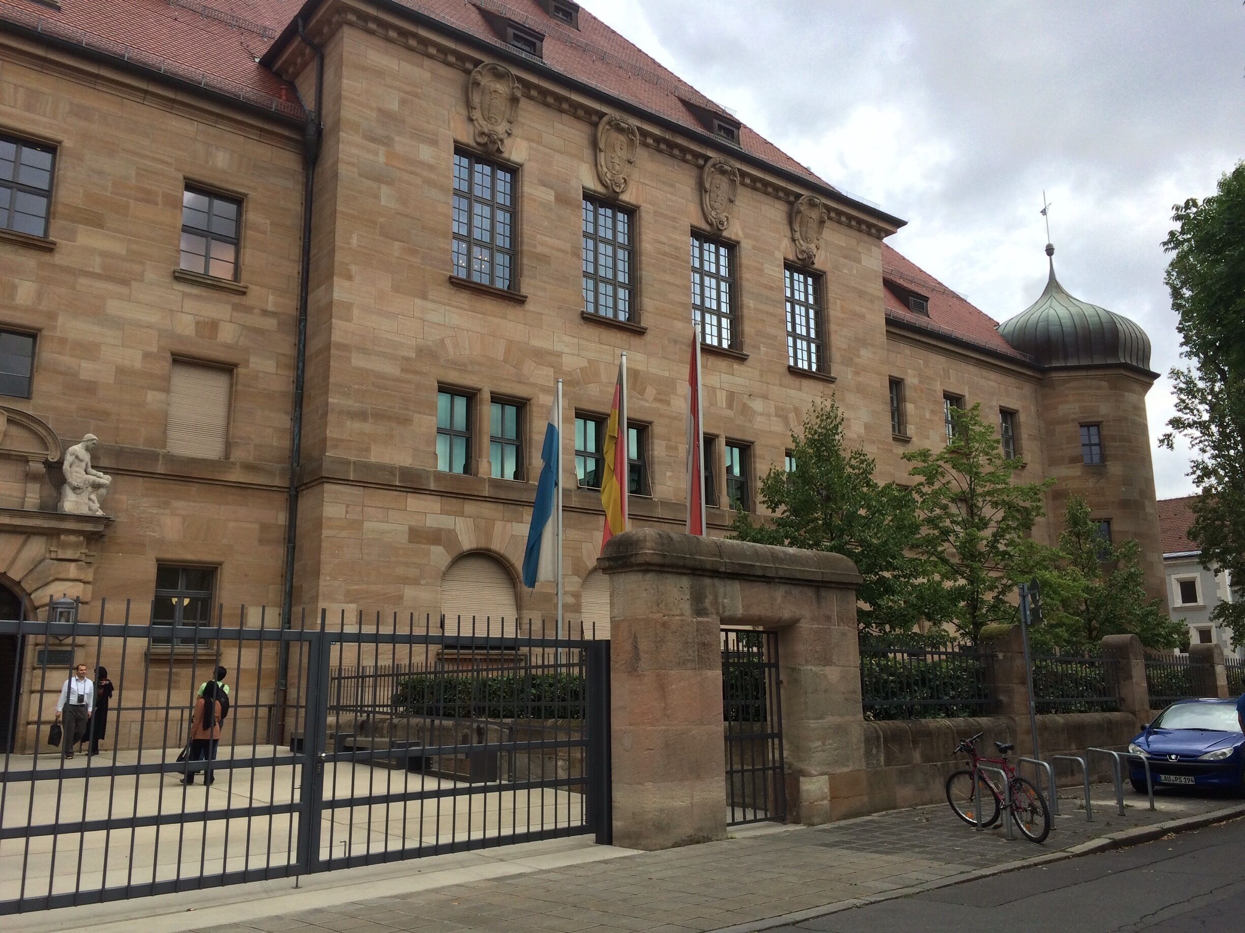 A historic building with a stone facade, a dome, and multiple flags.