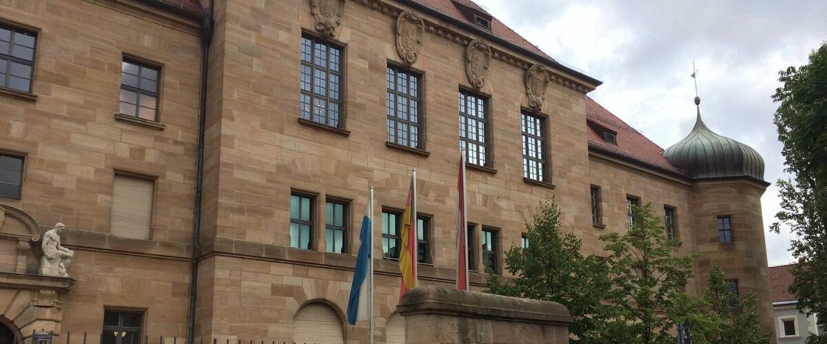 A historic building with a stone facade, a dome, and multiple flags.