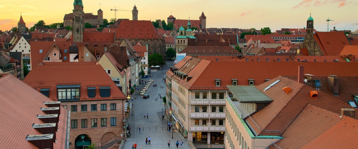 A historic town square with cobblestone streets, traditional buildings, and a prominent church spire.