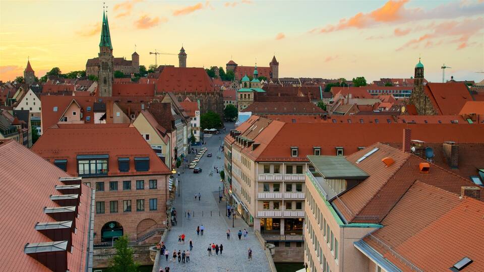 A historic town square with cobblestone streets, traditional buildings, and a prominent church spire.
