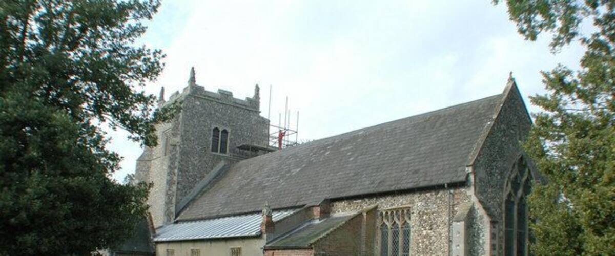 A church with a stone tower and a smaller building with a sloped roof.
