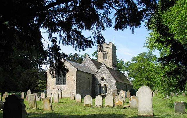 A church with a tall steeple and a graveyard with headstones.