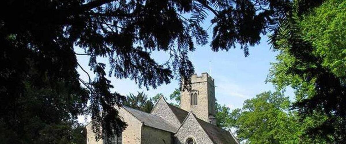 A church with a tall steeple and a graveyard with headstones.
