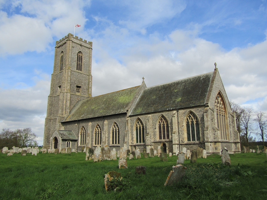 A historic church with a tall tower and a graveyard in front.