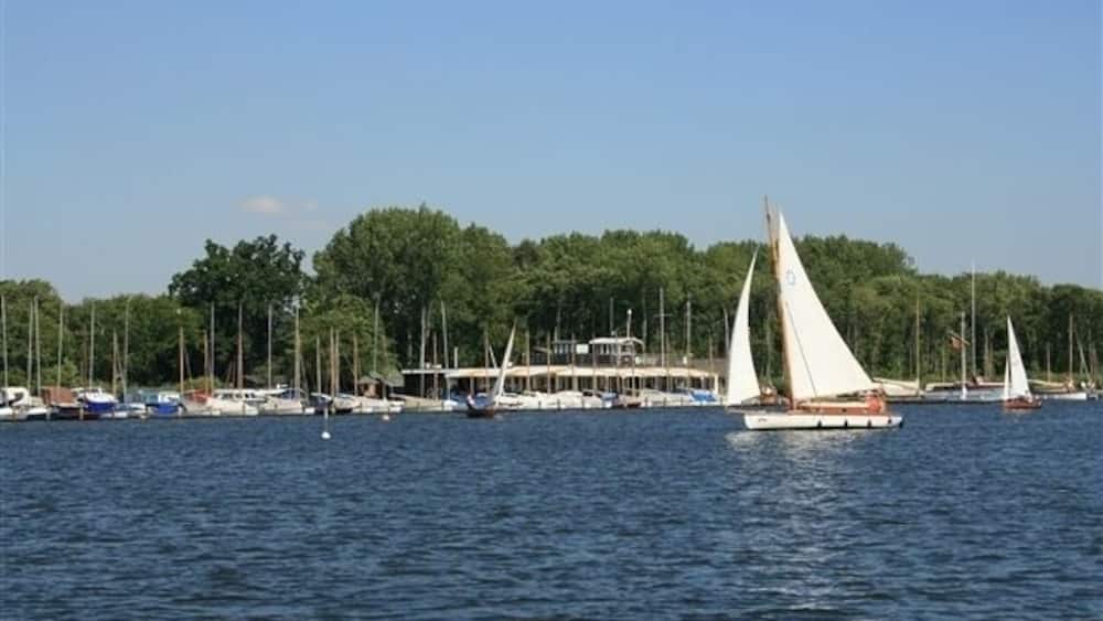 A marina with sailboats, a docked ferry, and a forested shoreline.