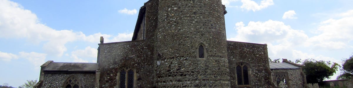 The west elevation and the round bell tower of the parish church of Saint Mary in the village of Roughton, Norfolk, England.
