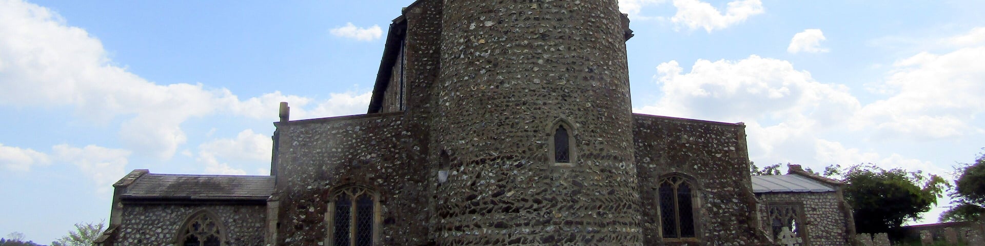 The west elevation and the round bell tower of the parish church of Saint Mary in the village of Roughton, Norfolk, England.