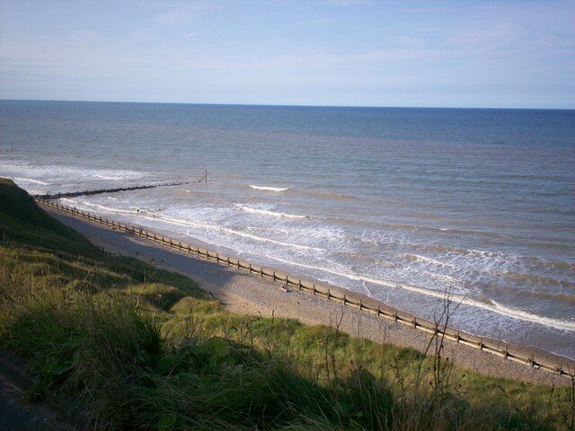 A coastal beach with a wooden fence along the shore.