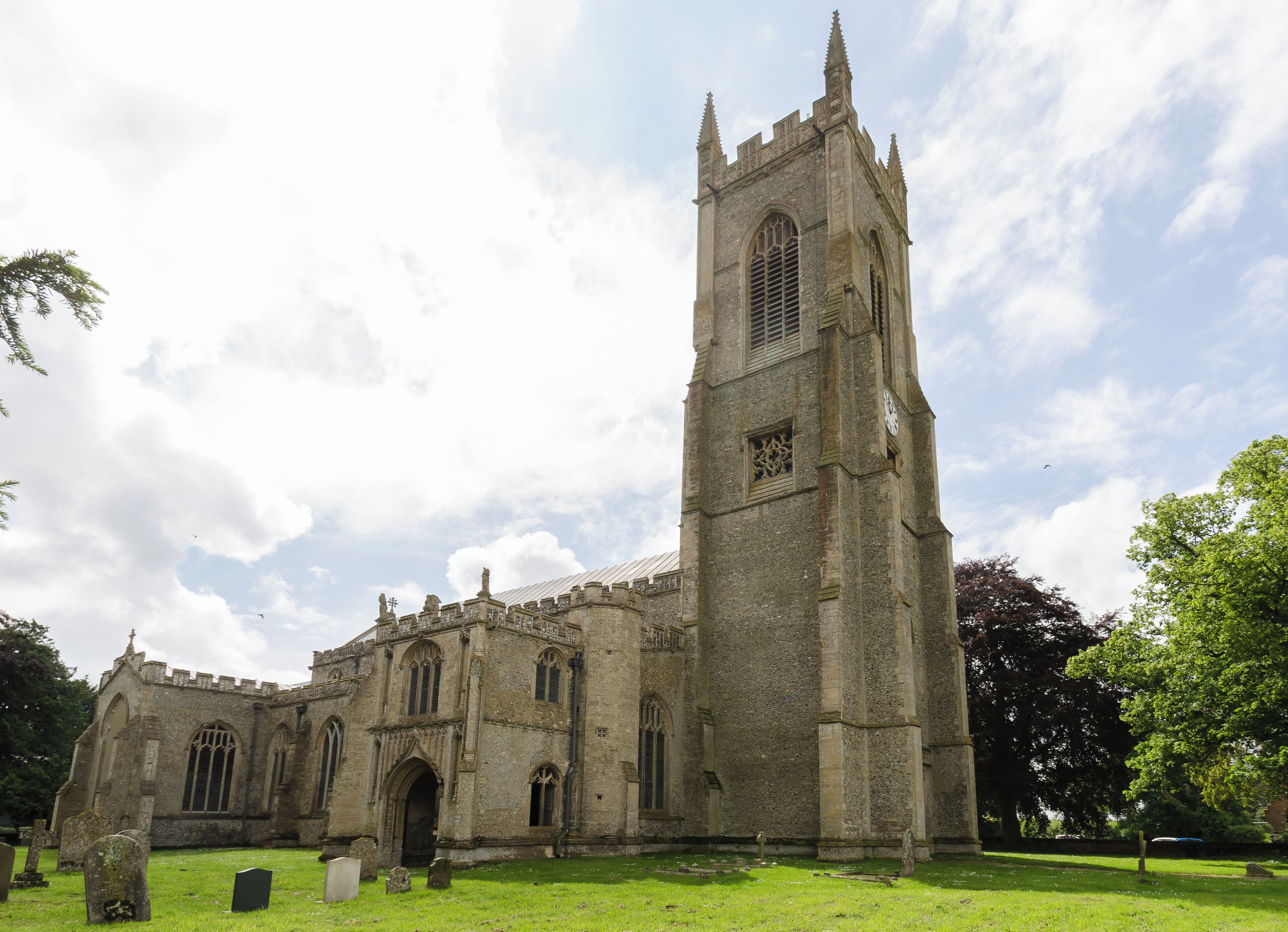 Grade I listed This large perpendicular church in a relatively remote location was built between around 1405 and 1420. It was financed by at least four Lords of Manors and other men with wealth acquired from wool. There were at least six Guilds Chapels, and a chaplain and clerks in each Chapel prayed daily for donors' souls. There is a west tower, north and south porch with parvises, nave with clerestory, north and south aisles, north and south transepts and chancel. The west tower is of four stages, the last stage was built around 1511. There is a west door with censing Angels and Shields over it. The centre of the tower has a "sound hole" with delicate tracery. The top has richly decorated battlements. There are eight bells. The north and south porches are of two storeys, with stair turret access. The north porch parvise has a vaulted ceiling with carved bosses. There is the remains of a piscina, and this was probably a Lady Chapel. The south porch has a standard beamed roof, and the parvise was probably a Treasury, as the timbers of the roof have iron bands for protection. The nave has six-bay arcades, the piers having four shafts. There is a tall clerestory, and a window over the chancel arch. The chancel has a seven light east window of plain glass with some mediaeval glass in the tracery depicting the nine orders of Angels. The south transept has a four light south window and a three light east window. There is some mediaeval glass in the traceries. The north transept, originally a Chapel of Thomas Rose, d. 1441, was restored in 1910 by Sir Alfred Jodrell. He donated three stained-glass windows, some of which have original glass in the tracery. The western window represents the history of the church. The top four lights of the west window contain a message "Hear this ye old men and give ear all ye inhabitants of the land, hath this been in your days or even in the days of your fathers?". The north window has been blocked. The roof, like many other East Anglian churches, has carved Angels, most of which retain the original painting. There are also carved roof bosses in the chancel with various scenes, e.g. Nativity, Last Supper etc. There is a tall tower arch with a ringing gallery at the base of the tower. This also houses a balustrade and crane supporting the font canopy, all done in carved wood with original colours. The octagonal font from circa 1437 depicts the Seven Sacraments and The Crucifixion. There is also an inscription recording the donors John and Agnes Luce. The figures at the base have been mutilated. The pulpit is originally from the 15th century and was converted into a triple-decker in 1611. The stalls have carvings on the armrests and misericords, and the benches have carved poppy heads. Little remains of the original screen, but the panels still retain original paint depicting the Doctors of the Church and The Apostles. There are several good brasses in the church, including a "shroud brass" to John Brigge, and one to Geoffrey Boleyn. At the end of the 19th century the church was in a poor state of repair. Sir Woolmer White and Sir Alfred Jodrell plus others funded repairs. The restoration was sympathetically done. There is a modest two manual organ which was presented by Sir Woolmer White in 1912.