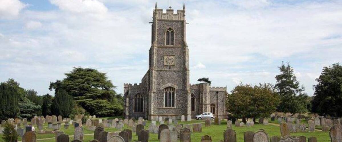 A church with a tall tower and a cemetery with numerous headstones.