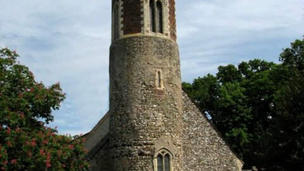 Une église en pierre dotée d’un haut clocher et de fenêtres en arc.