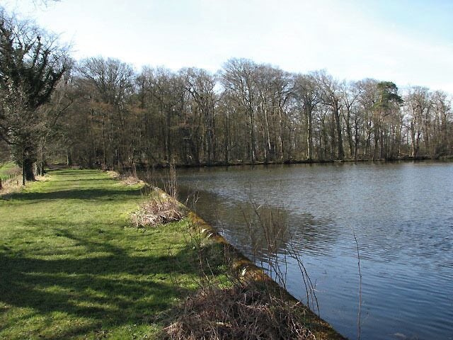 Footpath past Felbrigg Pond. The woodland seen in the background is Common Plantation. The history of Felbrigg estate dates back to the middle ages, when a member of the Norman family of Bigod took the name Felbrigg and built a manor house on the site of the present Hall, in the early 15th century. In around 1450 Felbrigg was acquired by John Wyndham, a wealthy merchant from the Norfolk town of Wymondham. The manor house was altered and added on to by following generations until a family member, "Mad Windham", almost ruined the estate and was forced to sell it in 1863, with all its contents. The estate was purchased by John Ketton, a Norwich merchant, whose daughter married a distant cousin of "Mad Windham". Their grandson, Robert Wyndham Ketton-Cremer (d. 1969) bequeathed the Felbrigg Hall and estate to the National Trust. See > 724631 for view of Felbrigg Hall.