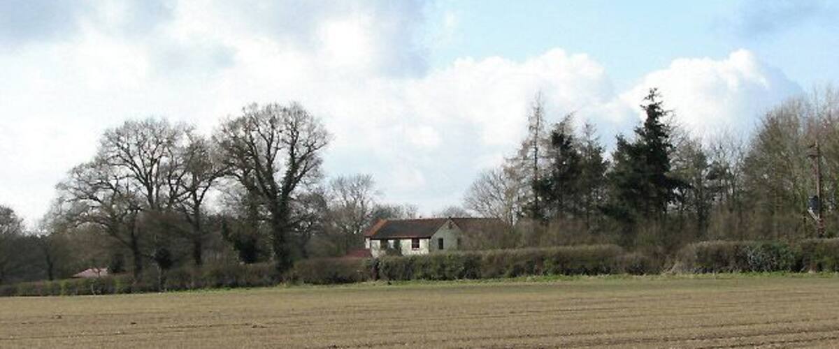 A plowed field with a house in the background.