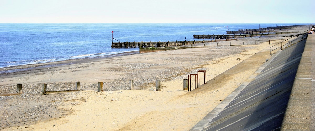 A sandy beach with a wooden pier extending into the sea.