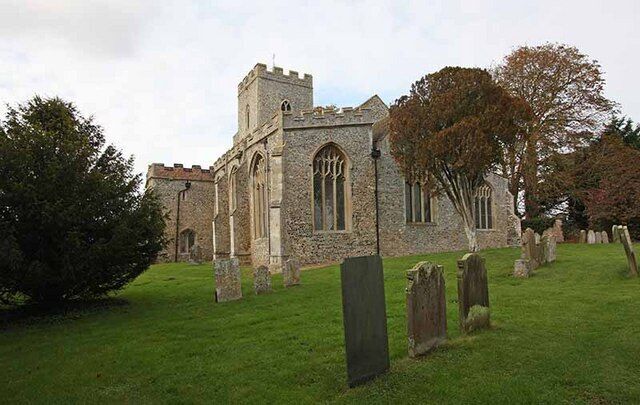 A historic stone church with a tower and arched windows, surrounded by a cemetery with headstones.