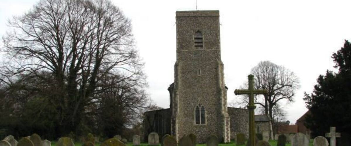 A church with a tall tower and a graveyard with numerous headstones.