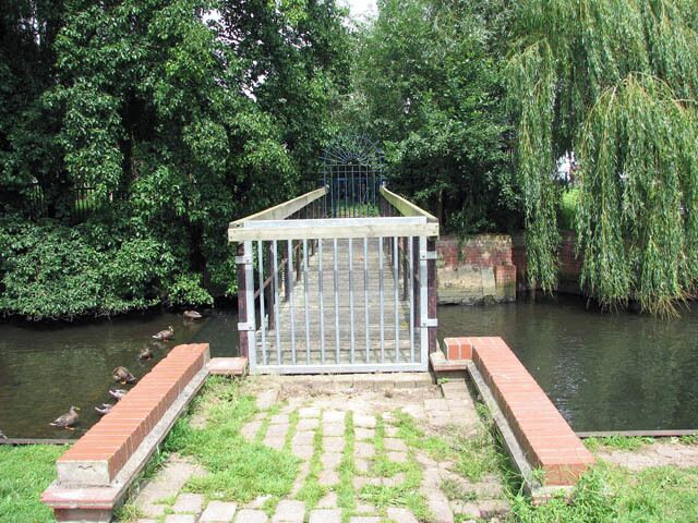Footbridge with blocked access across the River Chet. Ducks are sitting above the weir to the left of the bridge. Loddon is a market town in the Broadland district in South Norfolk, located on the River Chet, where there is a marina and staithes once used by the wherries. The watermill > 1418845 by the bridge across the river is recorded to be the oldest building in the town. The town centre has been designated as a conservation area and is made up of many period properties > 1418870. Most of the village shops > 1418876 are situated along Bridge Street > 1418866 - the main thoroughfare, as is Holy Trinity church > 525219.