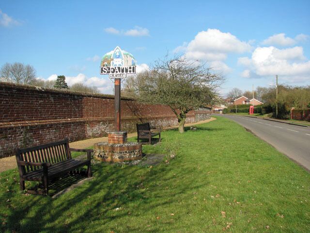 A park with a bench, a signpost, and a brick wall.