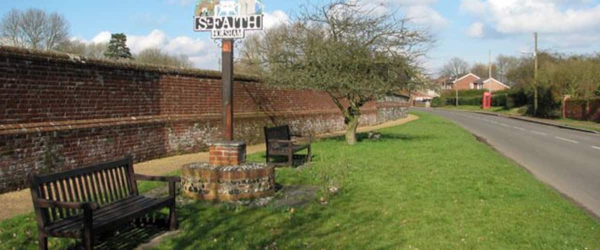 A park with a bench, a signpost, and a brick wall.